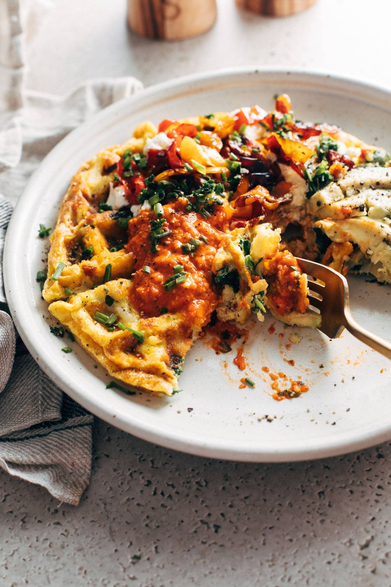Fork taking a bite out of a loaded egg waffle