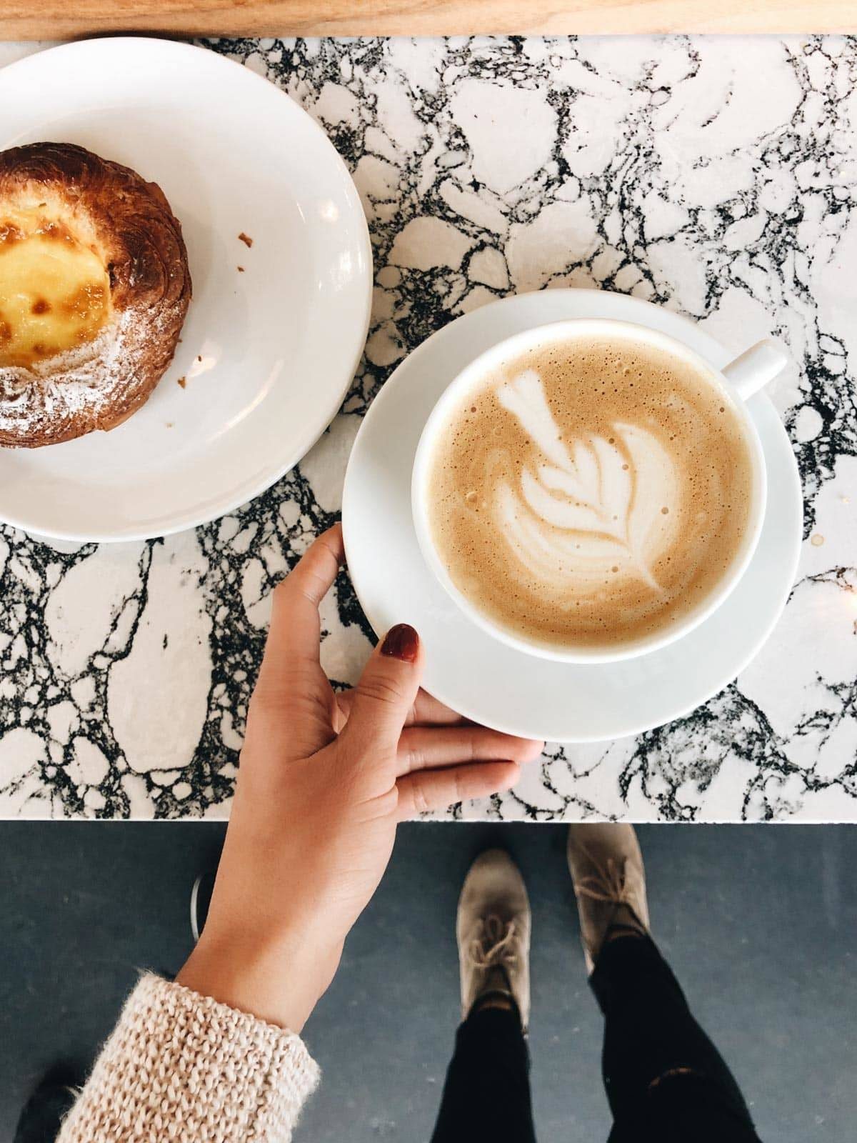 Coffee in a cup with creamer made into a design on it.
