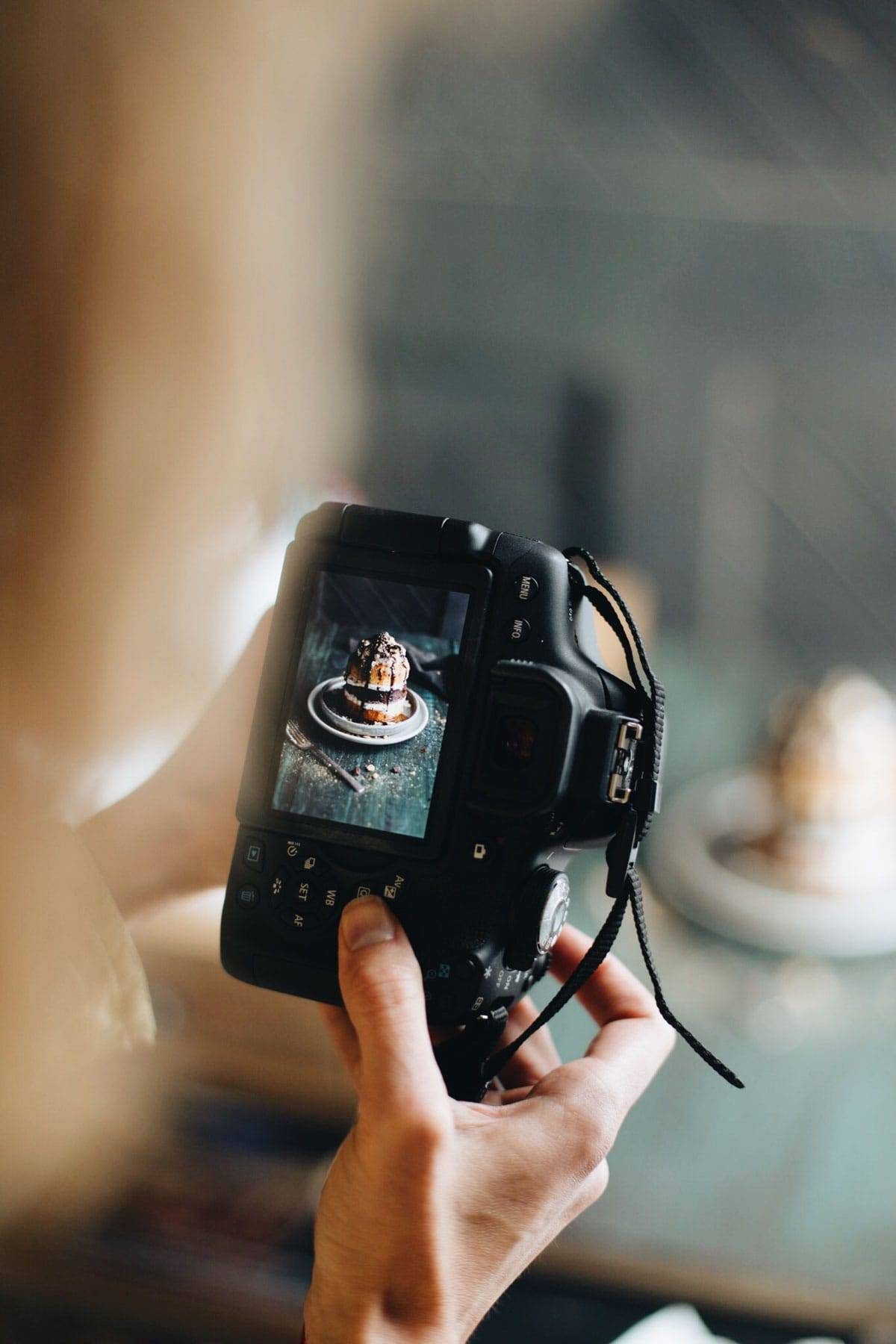 Hands holding a camera taking a photo of food.
