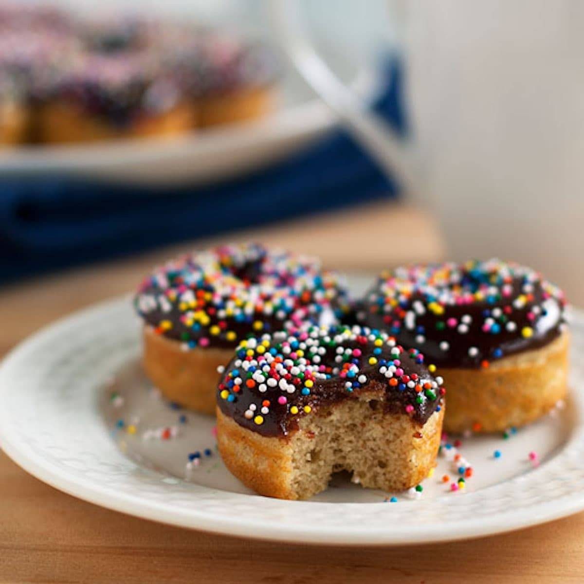 Chocolate glazed baked mini donuts with sprinkles on a plate.